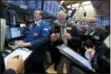  ?? RICHARD DREW — THE ASSOCIATED PRESS ?? Specialist Patrick King, left, works with traders at his post Tuesday on the floor of the New York Stock Exchange.