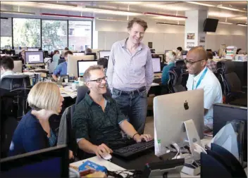  ?? Office. ?? Journalist Luke Harding (centre standing) speaking with colleagues in the Guardian