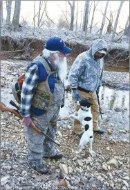  ?? NWA Democrat-Gazette/Flip Putthoff ?? Gary Wellesley (left), Chris Denham and squirrel dog Spec start their hunt on a frosty morning.