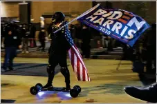  ??  ?? A Biden/harris supporter rides an electronic skateboard inn Washington DC