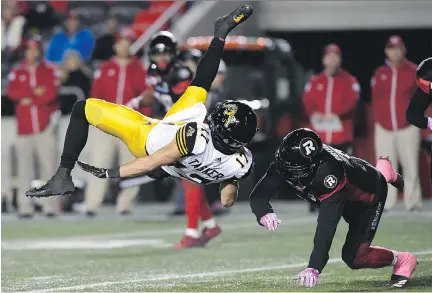  ?? JUSTIN TANG./THE CANADIAN PRESS ?? Tiger-Cats wide receiver Luke Tasker gets upended by the Redblacks’ Antoine Pruneau in Ottawa on Friday.