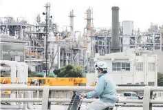  ??  ?? A worker cycles near a factory at the Keihin industrial zone in Kawasaki, Japan. — Reuters photo