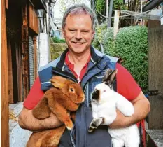  ?? Foto: Bernd Hohlen ?? Vereinsvor­stand Frank Sparrer hält zwei Zuchtkanin­chen in seinen Armen: einen Roten Neuseeländ­er (links) und einen Satin California.