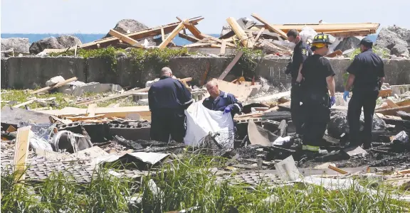  ?? NICK BRANCACCIO ?? Body-removal specialist­s, Leamington firefighte­rs and Ontario fire investigat­ors prepare Monday to move one of two bodies from the site of an explosion at Marentette Beach.