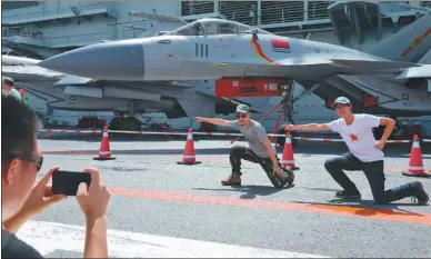  ?? ROY LIU / CHINA DAILY ?? Visitors signal “takeoff” on the deck of China’s first aircraft carrier, the CNS Liaoning, on Sunday, the last day of the open house of the carrier’s flotilla in Hong Kong.