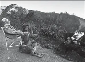  ?? Los Angeles Times/MEL MELCON ?? Richard Wangoe and Zoe, his Australian heeler, sit by a fire and take in the sunset from the top of his 54-acre property in Big Sur, Calif.