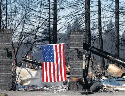  ?? AP PHOTO ?? An American flag hangs on a burned home Sunday in Santa Rosa, Calif. A state fire spokesman says it appears firefighte­rs are making good progress on deadly wildfires that started a week earlier, devastatin­g wine country and other parts of rural...