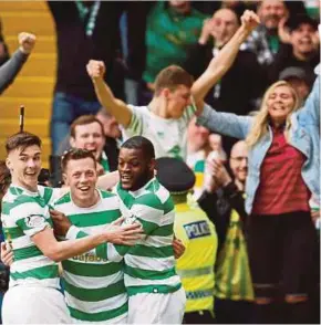 ?? REUTERS PIC ?? Celtic players celebrate in front of their fans after beating Rangers 5-0 to retain their Scottish Premiershi­p title yesterday.