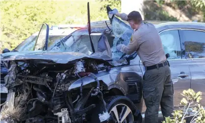  ??  ?? A law enforcemen­t officer looks over a damaged vehicle following last week’s rollover accident involving golfer Tiger Woods in the Rancho Palos Verdes suburb of Los Angeles. Photograph: Ringo HW Chiu/AP