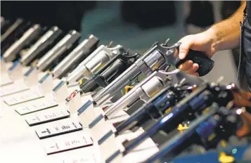  ?? JOHN LOCHER AP FILE ?? Handguns are displayed at a trade show in Las Vegas. Beginning in 2009, handguns purchased for personal protection began to outsell rifles in the United States.