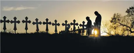  ?? ERIC GAY/THE ASSOCIATED PRESS ?? Kenneth and Irene Hernandez pay their respects Monday as they visit a makeshift memorial with crosses placed near the scene of a shooting at the First Baptist Church of Sutherland Springs in Sutherland Springs, Texas. A man opened fire inside the...