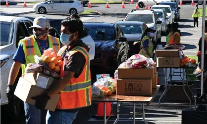  ?? Photograph: Robyn Beck/AFP/Getty Images ?? Volunteers at a food bank in Los Angeles help load supplies into people’s cars. Demand has increased by 145% since the start of the pandemic.