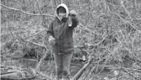  ?? ALISON JENKINS/JOURNAL PIONEER ?? Johanna Kelly stands in the Barbara Weit River holding a perfume bottle from a large trash heap.