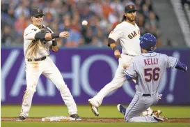  ?? JASON O. WATSON/GETTY IMAGES ?? Giants’Joe Panik turns a double play past the sliding Ty Kelly of the Mets during the third inning of Thursday’s wild National League game at AT&T Park.