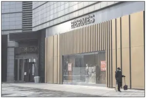  ??  ?? A cleaning person walks past an Hermes store in Beijing in early February. The luxury retailer has reopened all but two of its stores in mainland China.
(Bloomberg News/Giulia Marchi)