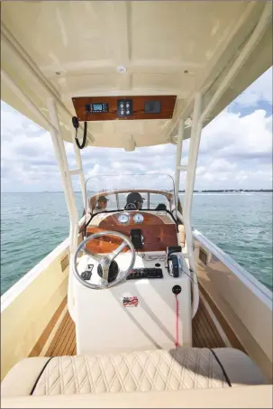  ??  ?? Le poste de pilotage reçoit un tableau de bord en bois verni et un grand volant en inox réglable très agréable. Le T-top bénéficie d’un emplacemen­t pour l’électroniq­ue.