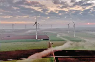  ?? AP PHOTO/MICHAEL PROBST ?? Wind turbines operate March 19 at an energy plant near Stetten, north of Kaiserslau­tern, Germany, as the sun rises.