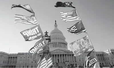  ?? JACQUELYNM­ARTIN/AP ?? Flags fly near theU.S. Capitol as supporters ofPresiden­tDonaldTru­mpattend marches Saturday inWashingt­on.