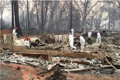  ?? The Associated Press ?? ■ Volunteer rescue workers search for human remains in the rubble of homes burned in the Camp Fire in Paradise, Calif., on Nov. 15, 2018. Climate change makes hurricanes wetter and more powerful, but it also increases the frequency of heat waves like ones that scorched the Pacific Northwest the last two summers, killing scores of mostly aged people.