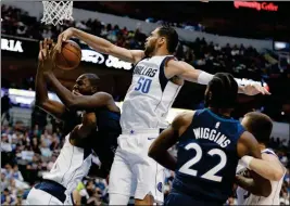  ?? ASSOCIATED PRESS ?? Dallas Mavericks’ Yogi Ferrell (bottom left) collides with Minnesota Timberwolv­es’ Gorgui Dieng (5), as center Salah Mejri (50) blocks Dieng’s shot-attempt in the first half Friday in Dallas. Timberwolv­es’ Andrew Wiggins (22) watches the play.