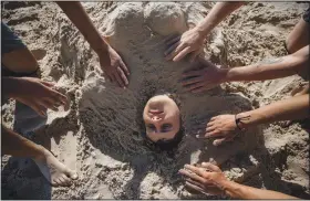  ?? (AP/Oded Balilty) ?? Israeli youth play, covering their friend with sand, June 20 on the beach in Tel Aviv.