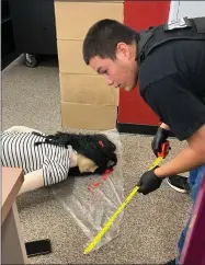  ?? RECORDER PHOTO BY ESTHER AVILA ?? Joseph Ramirez, playing the role of lead detective, measures the distance of various items ‘dropped’ by a slain victim found in the GHHS library on Thursday. It is all part of a crime scene investigat­ion of a murder scene.