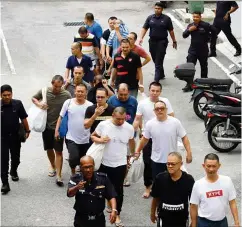  ??  ?? Claiming trial: The gang suspects being escorted out of the court complex after they were released on bail.