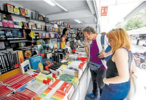  ?? // ÁNGEL RODRÍGUEZ ?? Dos personas observan el muestrario en uno de los puntos de venta de la Feria del Libro