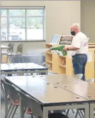  ??  ?? Farmington High Principal Jon Purifoy sprayed a sanitizer to clean the media center at the high school.