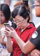  ?? STRINGER/AFP ?? Chen Peijie, China’s consul-general in Sabah, checks her phone at a jetty in Kota Kinabalu yesterday as she awaits developmen­ts.