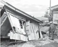  ??  ?? PERIKSA: Anggota APM memeriksa bahagian belakang rumah kayu yang runtuh di Kampung TAR.