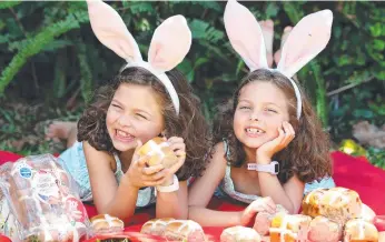  ?? ?? Lily and her sister Rose who has undergone a battle with anaplastic large cell lymphoma, sample some hot cross buns, which will go on sale at Coles from today to raise money for Redkite.