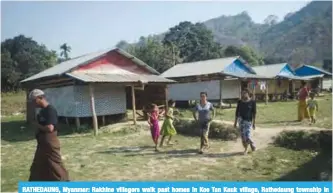  ??  ?? RATHEDAUNG, Myanmar: Rakhine villagers walk past homes in Koe Tan Kauk village, Rathedaung township in Myanmar’s Rakhine State.—FP