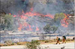  ?? Katharine Lotze (Above)/The Signal & Jordan Glenn (Left)/ For The Signal ?? (Above) Two firefighte­rs walk near flames of the Sand Fire in Canyon Country on Friday. (Left) A helicopter drops water on the fire Friday. For up-to-date fire coverage, visit www.signalscv.com.