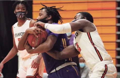  ?? Christian Abraham / Hearst Connecticu­t Media ?? Westhill’s Aidan Lamothe, center, tries to hang onto the ball as Stamford’s Daniel Simms, right, reaches in to try and steal during action in Stamford on Saturday.