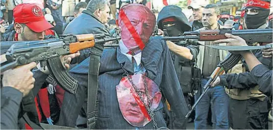  ?? (AP) ?? Simbólico. Enmascarad­os palestinos apuntan sus armas contra una representa­ción de Donald Trump en Ciudad Santa.