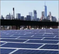  ?? MARK LENNIHAN — THE ASSOCIATED PRESS ?? A rooftop is covered with solar panels at the Brooklyn Navy Yard in New York. The Manhattan skyline is at top.