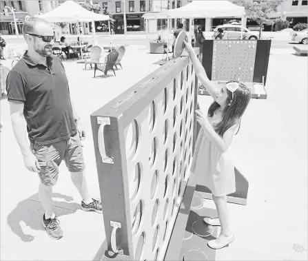  ?? PETER LEE WATERLOO REGION RECORD ?? Alex Russell and his daughter Lauren, 7, of Waterloo, play a giant Connect 4 game in the public square at the Waterloo Town Square, Waterloo, on Sunday. It was the first event of the season for Open Streets. The events run until September.