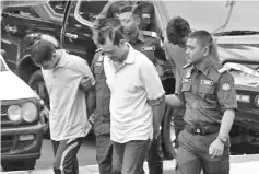  ??  ?? The suspects being escorted to the courthouse in Balik Pulau yesterday.