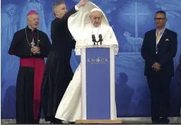  ?? — AP ?? An aide adjusts Pope Francis’ cape as he speaks at the Knock Shrine in Knock, Ireland, on Sunday. Pope Francis was on a two- day visit to Ireland.