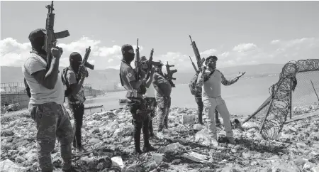  ?? RODRIGO ABD AP ?? Flanked by members of the G9 gang coalition, leader Jimmy Cherizier, aka Barbecue, right, talks to reporters near the perimeter wall that encloses Terminal Varreux, the fuel port in Port-au-Prince, Haiti, on Oct. 6, 2021. Since 1995, the U.S. Treasury has used the power of financial sanctions to cripple drug cartels in Colombia and Mexico, and most recently to pursue Russian oligarchs and Venezuelan­s associated with the regime of Nicolás Maduro. Now they are going after Haitians who they believe are financiall­y supporting armed gangs that reportedly control over 60% of the capital.