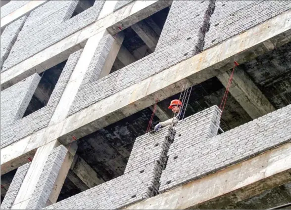  ?? HENG CHIVOAN ?? Brick by brick, a constructi­on worker cements together a wall of a building in Tonle Bassac commune in Daun Penh district