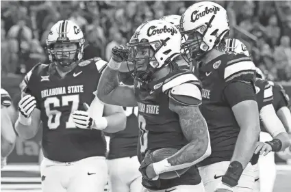  ?? PHOTOS BY THOMAS SHEA/USA TODAY SPORTS ?? OSU running back Ollie Gordon II (0) celebrates his rushing touchdown with teammates in the second quarter off a 31-23 win against Texas A&M on Wednesday at NRG Stadium in Houston.