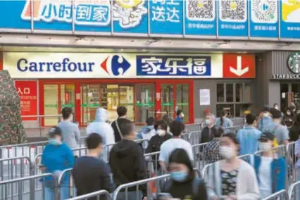  ?? ?? Residents in Wanli Subdistric­t line up in front of Carrefour’s Wanli store. — Zhou Shengjie