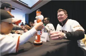  ?? Photos by Josh Edelson / Special to The Chronicle ?? Giants bullpen coach Matt Herges signs a nutcracker statue for a young fan Saturday at the Giants’ FanFest at newly renamed Oracle Park.