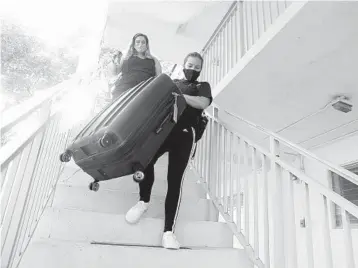  ?? AMY BETH BENNETT/SOUTH FLORIDA SUN SENTINEL ?? Palm Beach Atlantic University student Sophie Gonzalez helps Rachel Smalley, front, move out of an isolation dormitory.