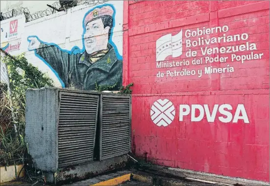 ?? CARLOS GARCIA RAWLINS / REUTERS ?? El logo de la compañía petrolera estatal de Venezuela, PDVSA, junto a un mural con la imagen de Chávez, en una gasolinera de Caracas