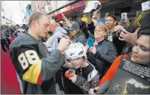  ?? Richard Brian ?? Las Vegas Review-journal @vegasphoto­graph Golden Knights defenseman Nate Schmidt autographs the helmet of Hunter Klingennei­er, 12, of Las Vegas, on Sunday at the Fremont Street Experience during the team’s first fan fest.