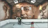  ?? INDRANIL MUKHERJEE / AGENCE FRANCE-PRESSE ?? A worker cleans the viewing area in front of a photo mural at the St+art Festival at Sassoon Dock in Mumbai on Thursday.
