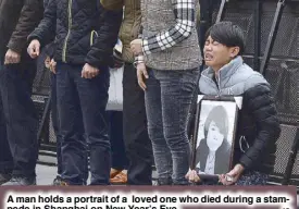  ?? AP ?? A man holds a portrait of a loved one who died during a stampede in Shanghai on New Year’s Eve.